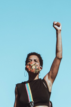 Black woman with fist raised wearing mask