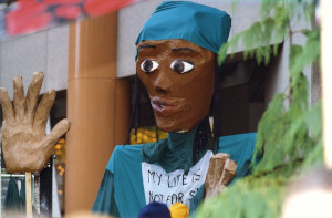 Giant black puppet with sign saying 'My Life is Not for Sale.'